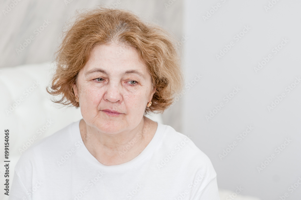 Upset senior woman sitting on bed at home Upset senior woman sitting on bed at home