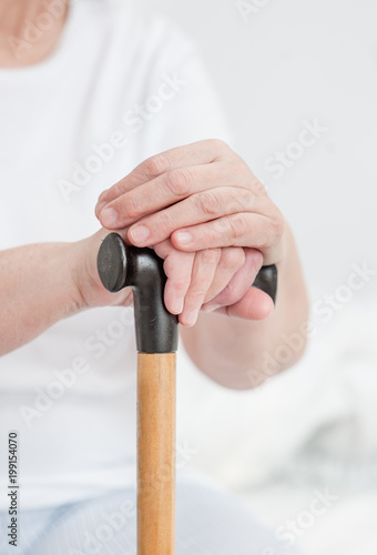 Hands of an old senior woman on a cane