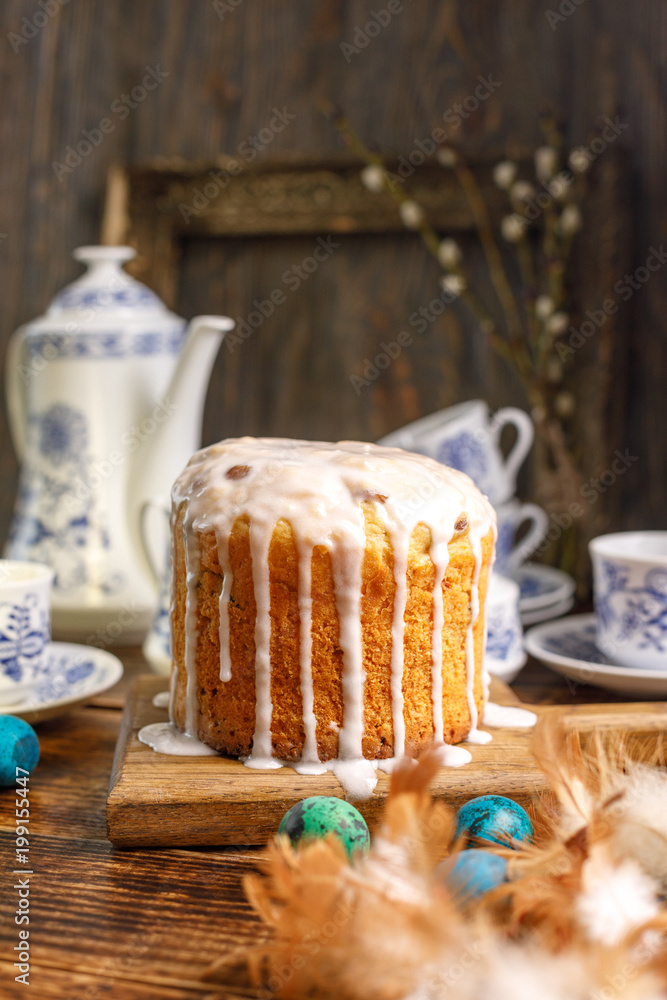 Easter greeting card. Tea in the village for Easter. Home Easter cake and painted eggs for the holiday. Beautiful tea set and Easter cake on a wooden background.