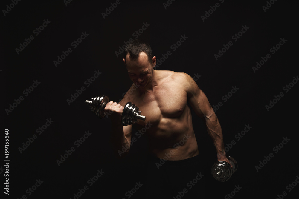 Strong athletic man with dumbbell showes naked muscular body Strong athletic man with dumbbell showes naked muscular body