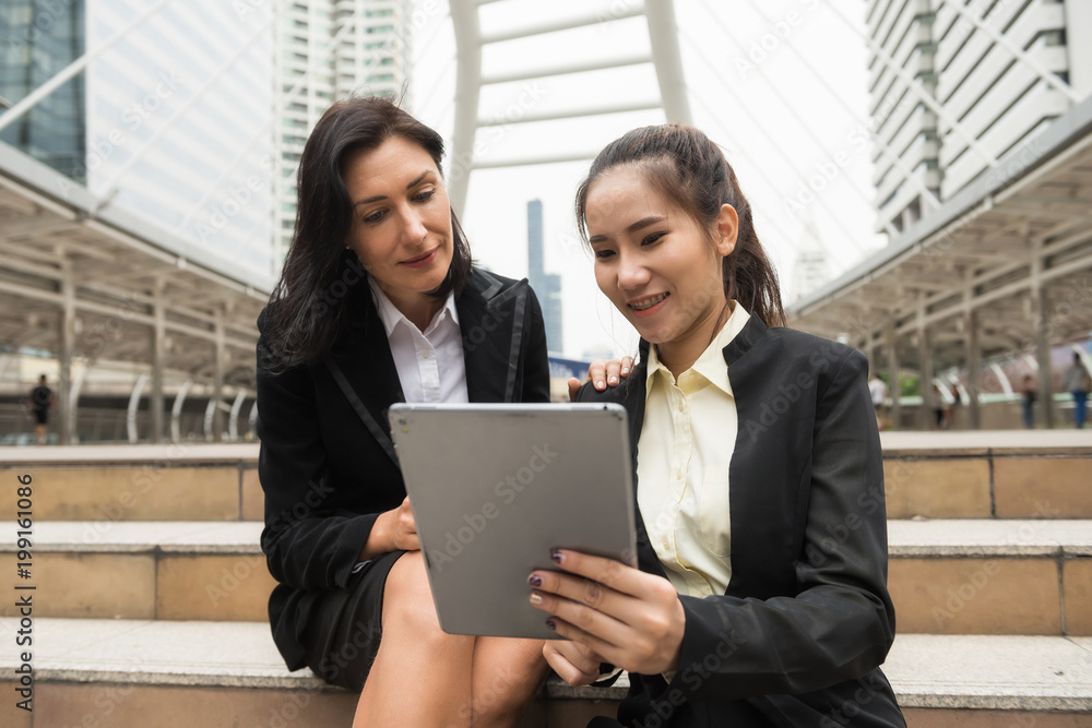Two business women with tablet in city Two business women with tablet in city