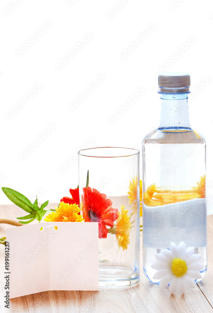 water bottle and glass of water with white note paper and flower on wood table in natural background, Concept drinking healthy and health care. water bottle and glass of water with white note paper and flower on wood table in natural background, Concept drinking healthy and health care.