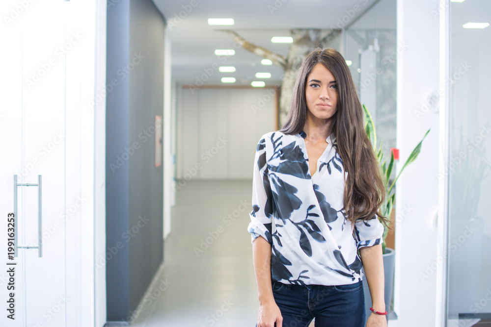 Portrait of young business woman standing in office hall. Portrait of young business woman standing in office hall.