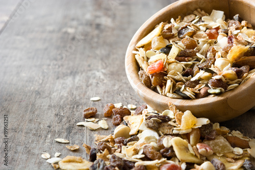 Muesli and dried fruit in wooden bowl on wooden table. Copyspace photo