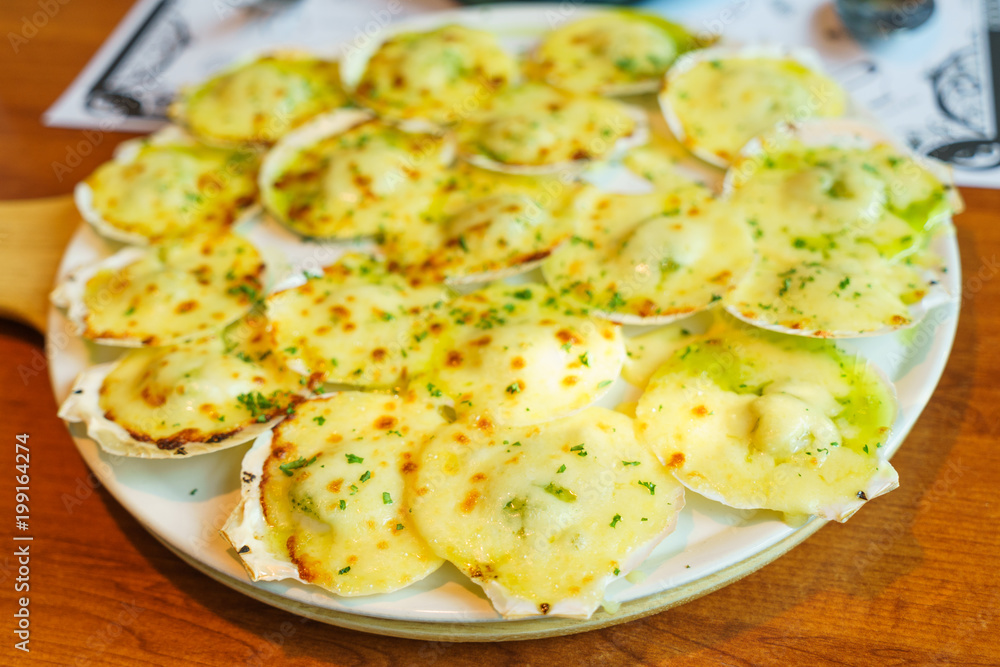 Grilled scallops with butter and cheese. Seafood grilled scallops on white plate Grilled scallops with butter and cheese. Seafood grilled scallops on white plate