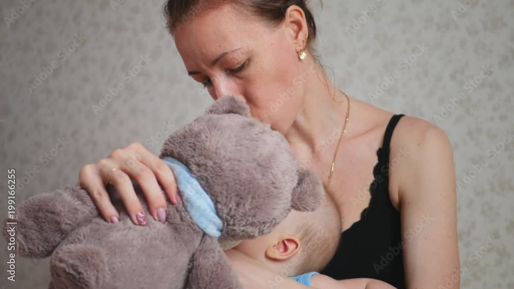 One year old baby boy inhaling from the inhaler, her mother holding her in the arms. Treatment of cough. Procedure of inhalation. One year old baby boy inhaling from the inhaler, her mother holding her in the arms. Treatment of cough. Procedure of inhalation.