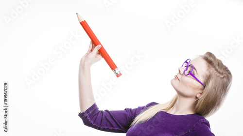 Smiling woman holds big pencil in hand