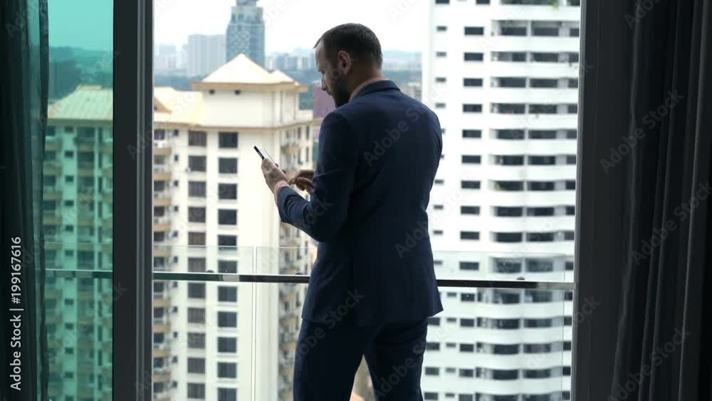 Young businessman texting on smartphone on balcony at home
