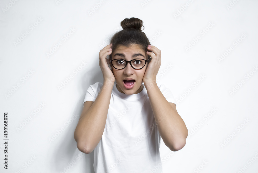 A frightened girl, a sense of fear and shock. A young woman grabs her head from the horror she sees. A frightened girl, a sense of fear and shock. A young woman grabs her head from the horror she sees.