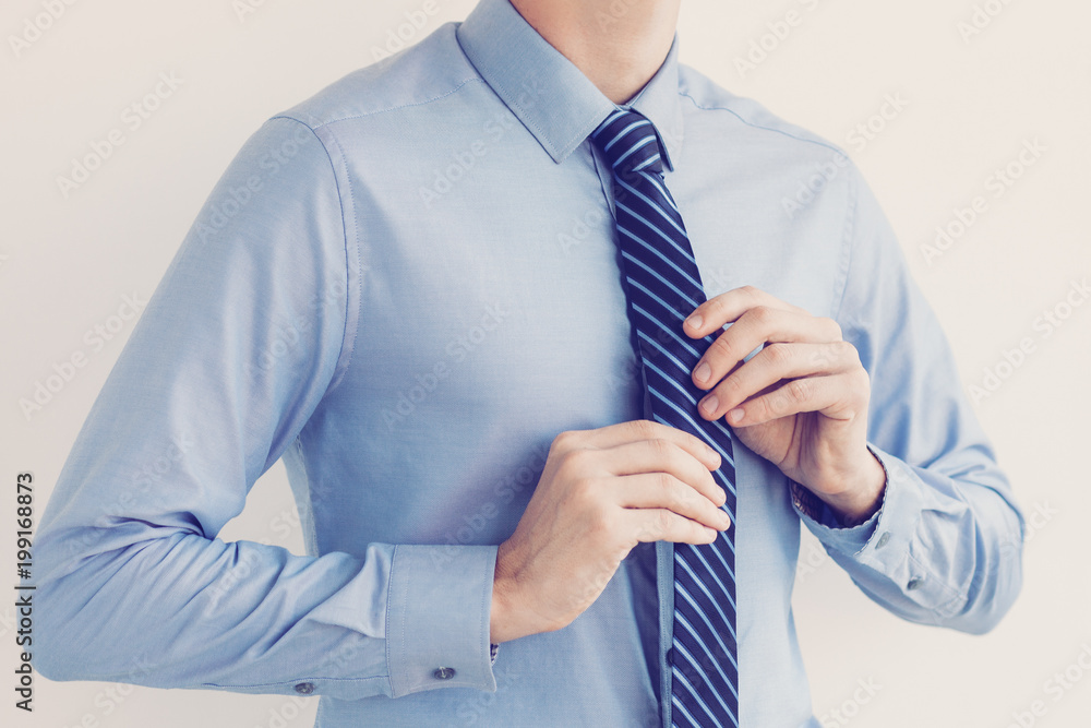 Cropped view of young business man adjusting his tie. Isolated view on white background. Cropped view of young business man adjusting his tie. Isolated view on white background.