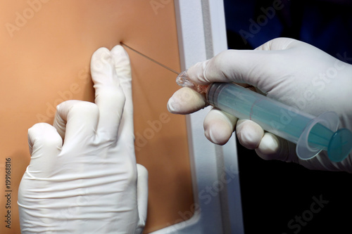 Hands in gloves making injection with a syringe for puncture. Simulation medical training model. Medical procedure concept, simulation medicine training.