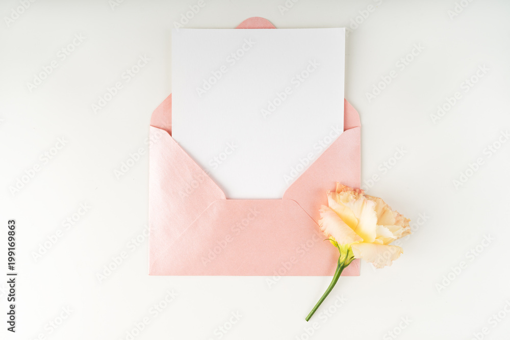 Minimal composition with a pink envelope, white blank card and flower eustoma on a white background. Mockup with envelope and blank card. Flat lay. Top view. Minimal composition with a pink envelope, white blank card and flower eustoma on a white background. Mockup with envelope and blank card. Flat lay. Top view.