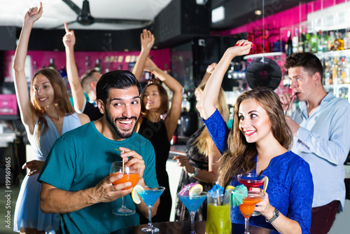 Man with woman are drinking cocktails on corporate party.