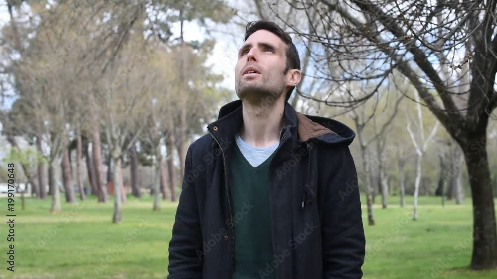 Hombre hombre joven dirigiéndose a cámara mientras pasea por el campo observando el cielo y los alrededores Hombre hombre joven dirigiéndose a cámara mientras pasea por el campo observando el cielo y los alrededores