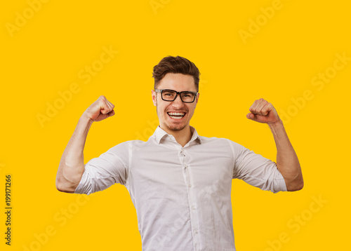 Young man in glasses holding hands up celebrating success