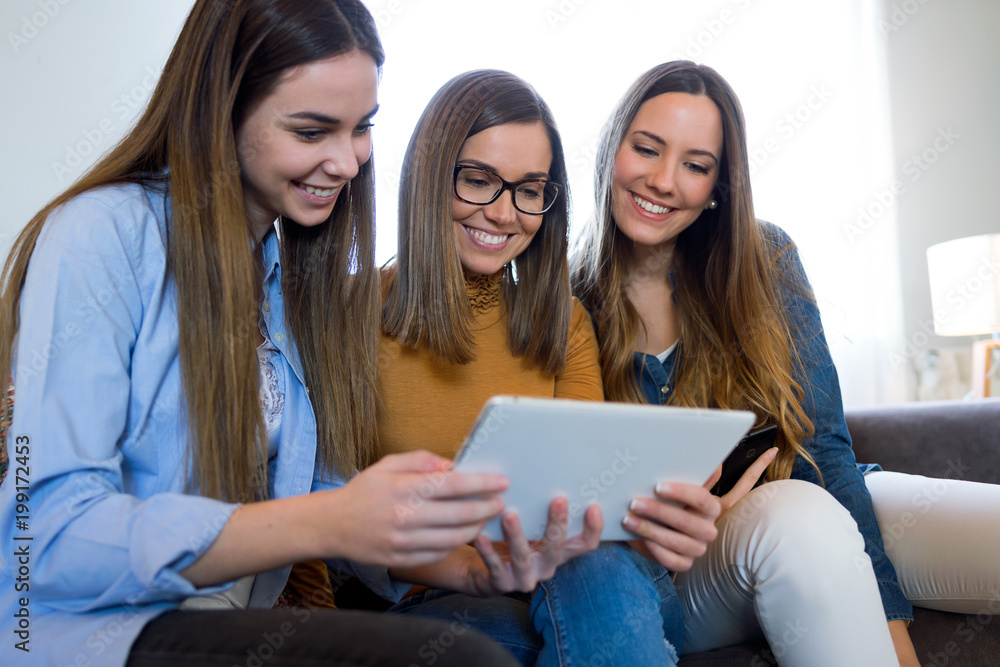 Three happy beautiful women using digital tablet at home. Three happy beautiful women using digital tablet at home.