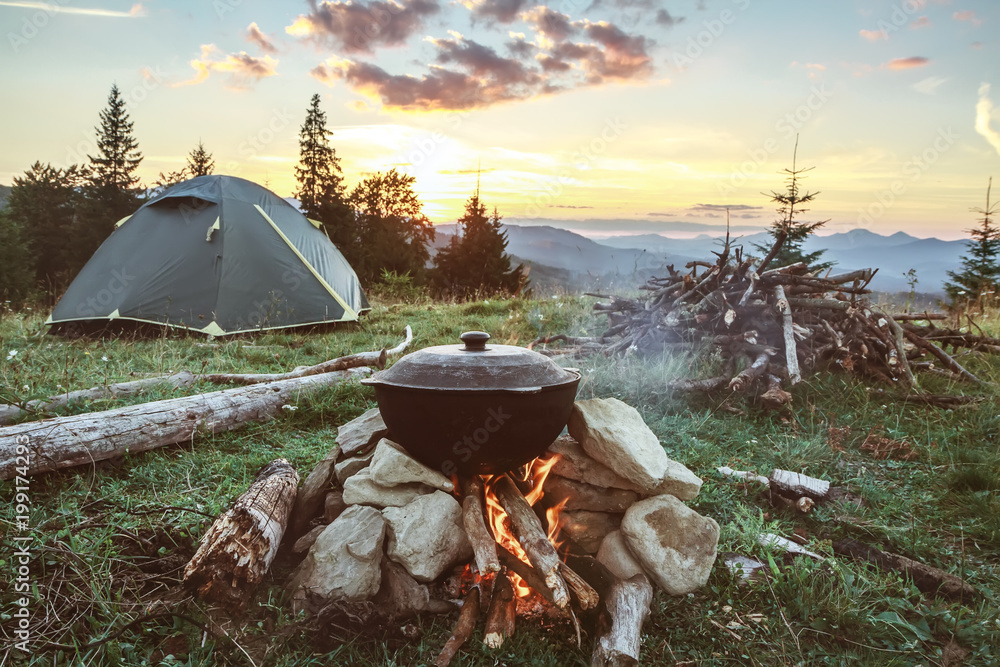 Tourist camp with fire, tent and firewood - obrazy, fototapety, plakaty 