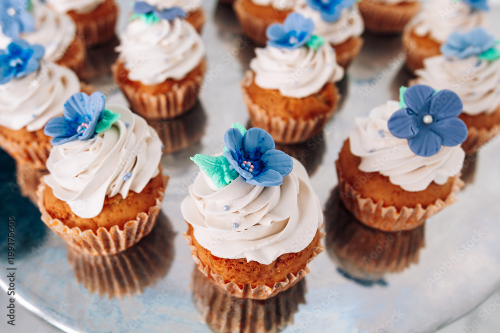 muffins with whipped cream and frosting on a silver table in stainless steel muffins with whipped cream and frosting on a silver table in stainless steel