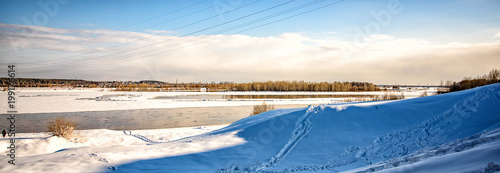 panorama of a winter landscape with a view of the river with floating ice floes