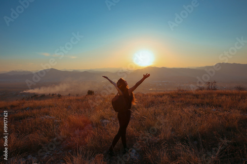 Sunset mountain. Tourist Free happy woman outstretched arms with backpack enjoying life in wheat field. Hiker cheering elated and blissful with arms raised