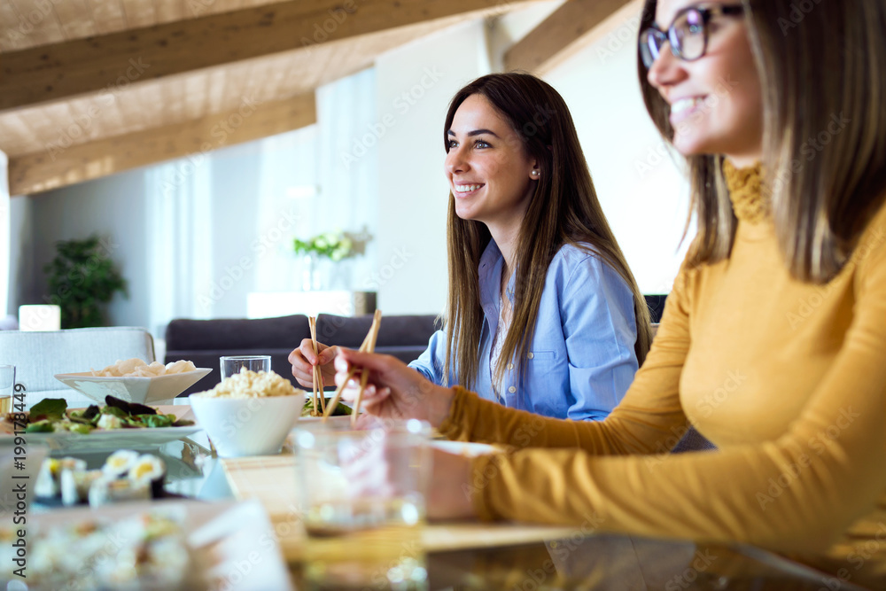 Two beautiful young women eating japanese food at home. Two beautiful young women eating japanese food at home.