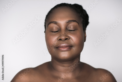 Young African woman with beautiful skin against a gray background  © mavoimages