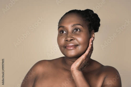 Young African woman smiling and touching her cheek 