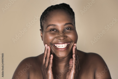 Young African woman smiling and touching her perfect complexion