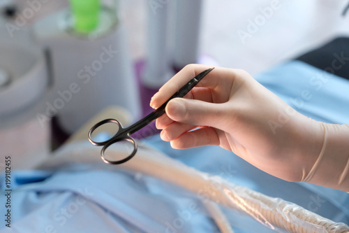 Hands of an assistant dentist in protective gloves with a tool in the treatment of a patient
