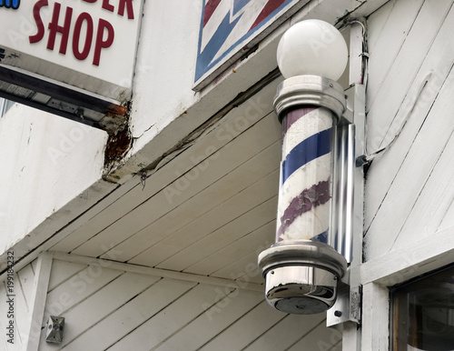 Barber shop pole on weathered white urban building 