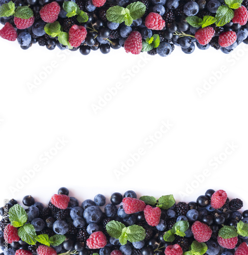 Mix berries and fruits at border of image with copy space for text. Ripe blueberries, blackberries and raspberries on white background. Top view.