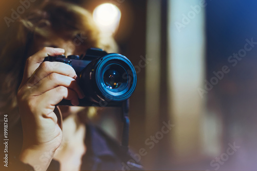 photographer girl enjoying night street in trip, traveler relax lifestyle concept, hipster hiker tourist making photo, holding in hands camera on background of evening city, blogger view in holiday