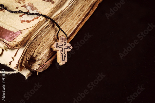 Wooden cross and old bible on a black background. 