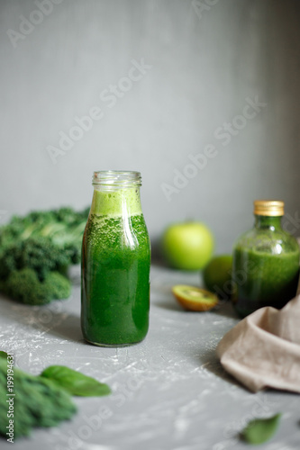 Healthy green smoothie with ingredients on gray background. Copy space