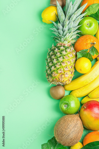 Variety of Different Tropical Summer Fruits. Pineapple Mango Coconut Citrus Oranges Lemons Apples Kiwi Bananas Arranged in Border on Turquoise Background.Healthy Diet Vegan Vitamins. Flat Lay