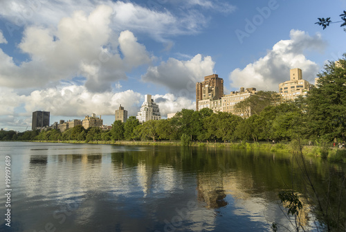 Central Park reflection/Residencial building overlooking the Central Park and reflecting into the lake on a summer cloudy afternoon.