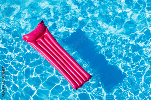 Pink inflatable mattress floating on water surface