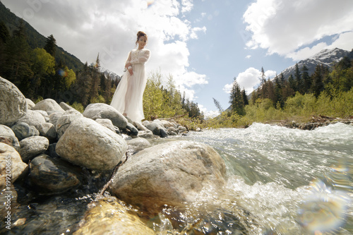 Beautiful boudoir sexy Bride in bathrobe dress. young girl fashion Stylish with bouquet on the nordic Karelian nature landscape background forest Waterfall river in mountains