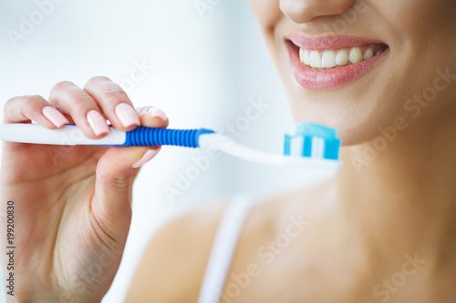 Beautiful Smiling Woman Brushing Healthy White Teeth With Brush. High Resolution Image