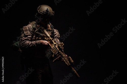Special forces United States soldier or private military contractor holding rifle. Image on a black background.