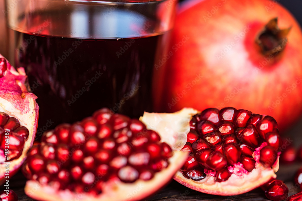 Ripe pomegranates with glass of juice on table Ripe pomegranates with glass of juice on table