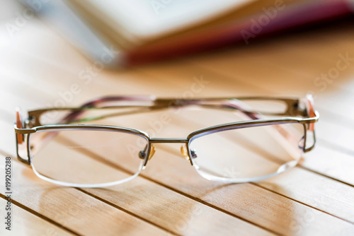 Glasses and open book on wooden table close