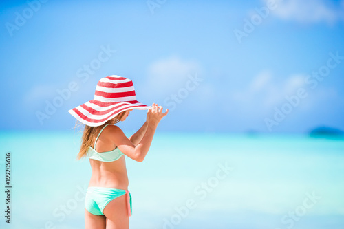Adorable little girl in big red hat on the beach