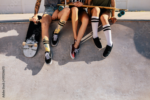 Legs of women sitting on ramp at skate park