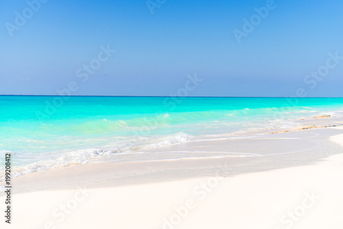 Idyllic tropical beach with white sand, turquoise ocean water and blue sky on Caribbean island