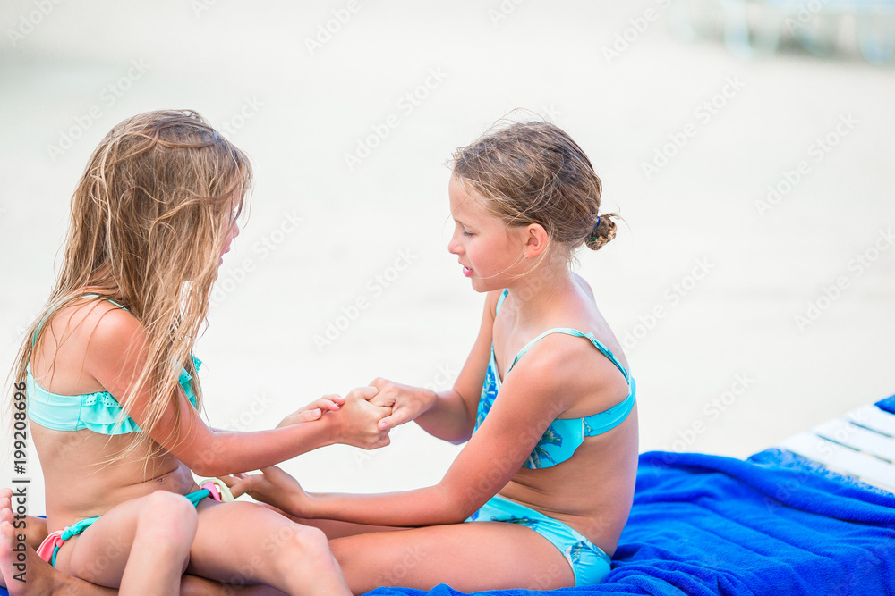 Little girls having fun at tropical beach playing together on sunbed Stock  Photo