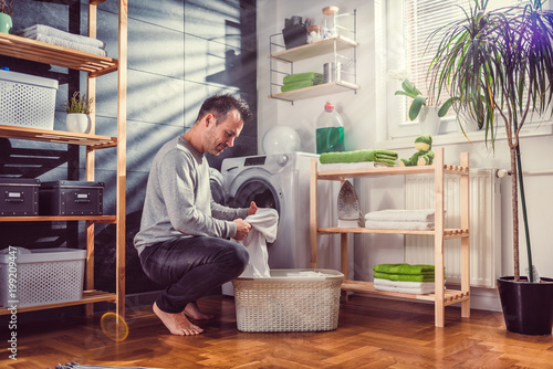 Fotografie Man putting clothes into washing machine