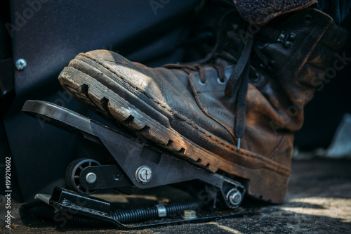 Foto Worker foot in large shoe or boot presses on pedal of industrial excavator or tr