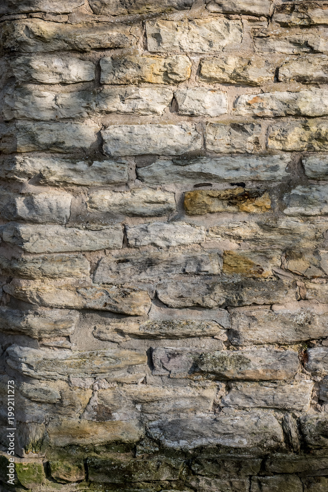 Old grey stone wall lighted by sunshine for texture or background shots. Old grey stone wall lighted by sunshine for texture or background shots.