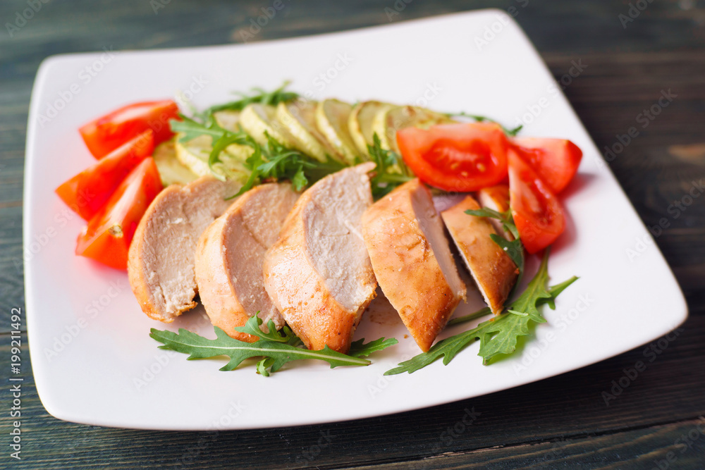 Diet food, proteins, healthy low-calorie meals concept. Baked chicken breasts with zucchini, tomatoes and arugula, close up Diet food, proteins, healthy low-calorie meals concept. Baked chicken breasts with zucchini, tomatoes and arugula, close up